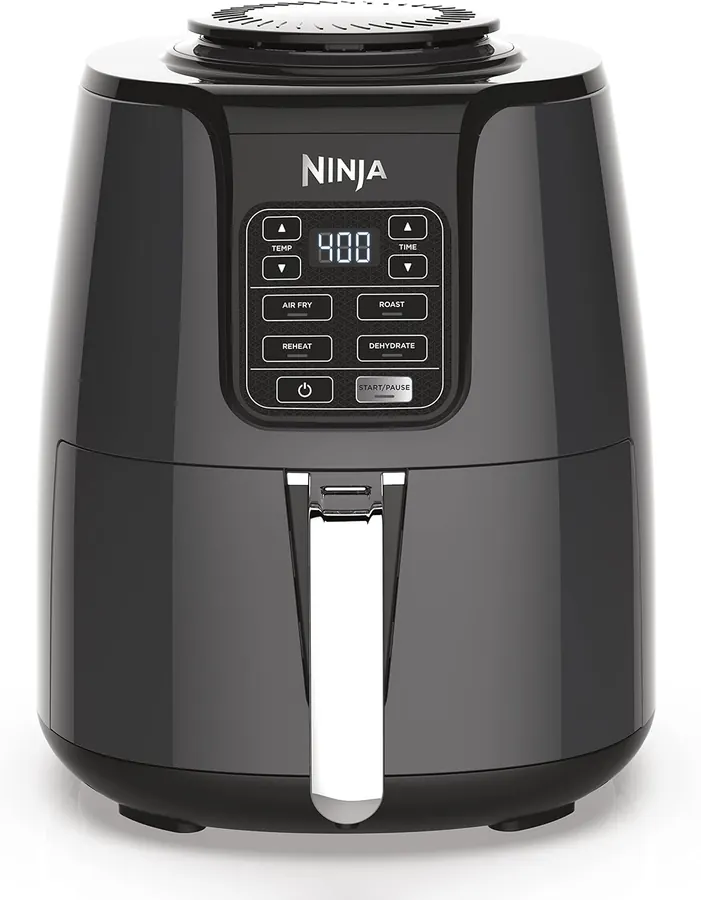 Hand placing a small sheet of seasoned salmon pieces into an open air fryer basket on a kitchen counter